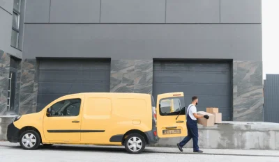 Furgoneta amarilla aparcada en un muelle de carga mientras un operario descarga cajas