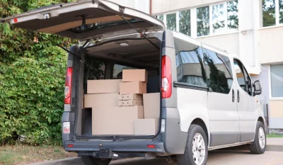 Furgoneta plateada con el portón trasero abierto y cajas apiladas en la zona de carga