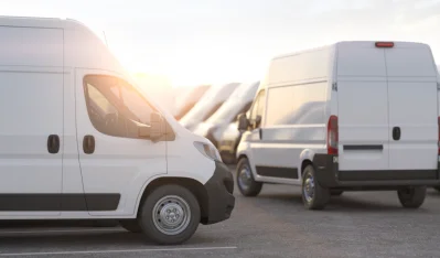Dos furgonetas blancas de carrocería alta aparcadas al atardecer con luz dorada