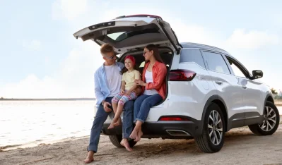 Familia en el maletero abierto de un SUV plateado en la playa