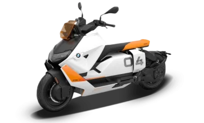 Escúter eléctrico blanco y naranja de perfil sobre fondo blanco de estudio