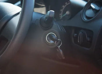 Contacto con llave junto al volante en el interior de un coche de tonos oscuros