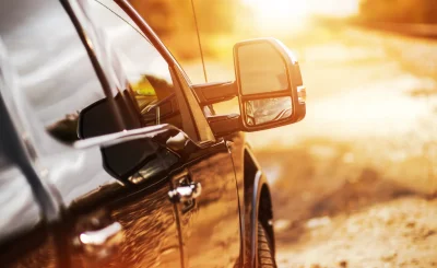 Espejo retrovisor lateral de un coche con destellos de sol y tonos anaranjados