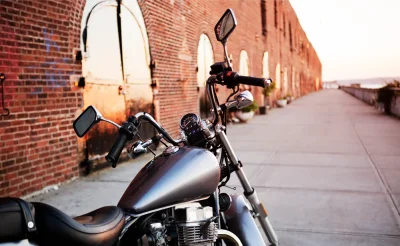 Moto custom negra con asiento bajo aparcada junto a una pared de ladrillo rojo