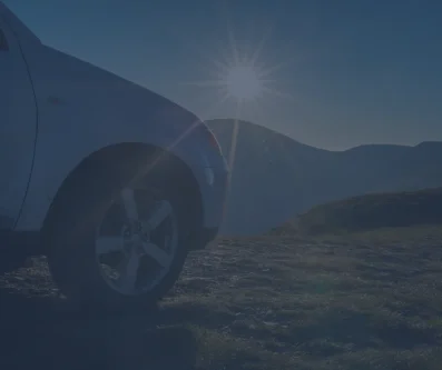 Detalle del guardabarros de un coche con el sol y las montañas al fondo