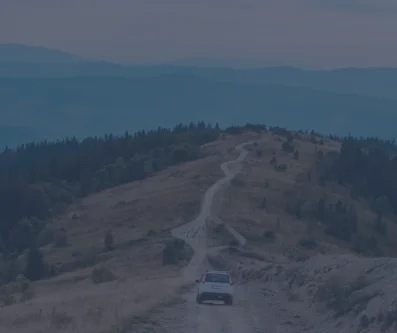 Vista aérea de una pista de montaña que sube por una loma, con un coche al pie
