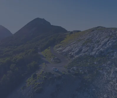 Ladera rocosa de montaña con prados dorados y un sendero que sube hacia la cima