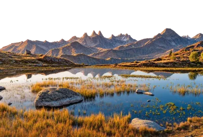 Lago de alta montaña con hierba dorada en las orillas y picos recortados al fondo