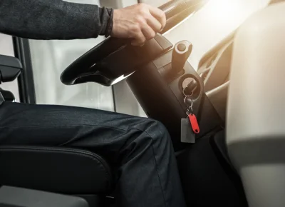 Conductor con la mano en el volante y llave colgando del contacto, con sol de frente