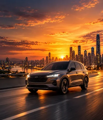 SUV gris en carretera junto a una ciudad con rascacielos al atardecer y el sol de frente
