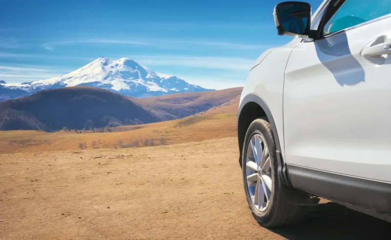 Lateral de un SUV blanco con las montañas nevadas y la estepa al fondo
